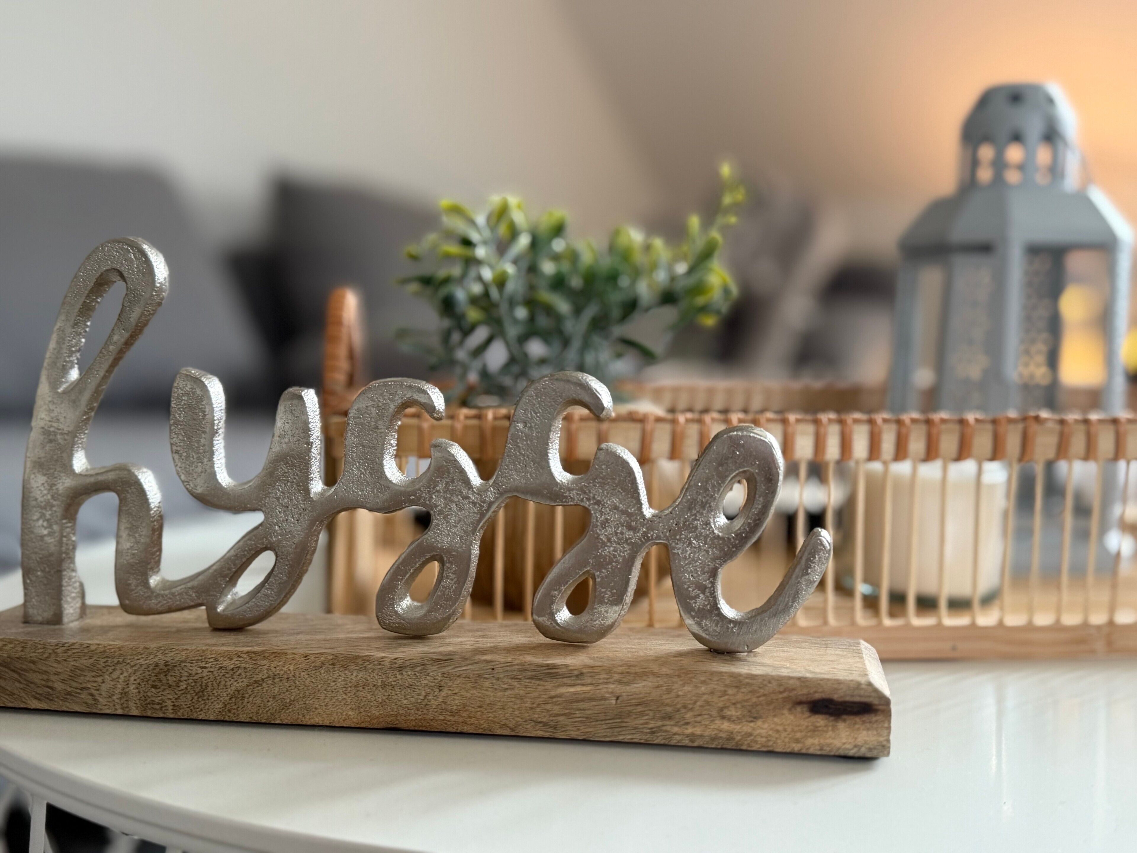 A decorative metal sign with the word 'hygge' on a wooden board.