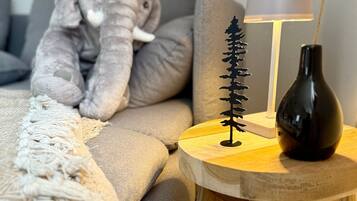 A cozy room with a sofa, a lamp, a small tree decoration, and a stuffed elephant toy.