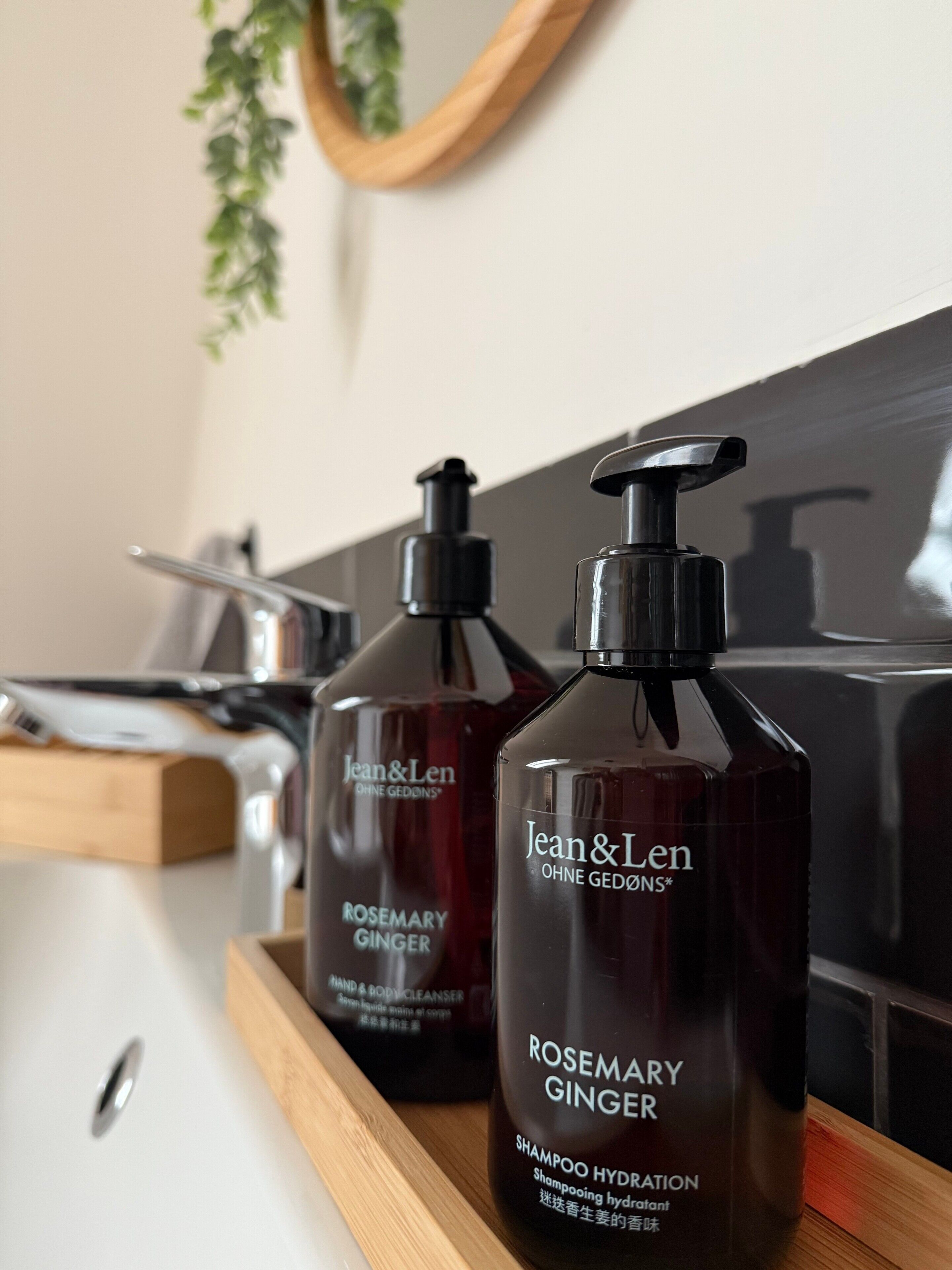 Two bottles of Jean & Len Rosemary Ginger Shampoo Hydration on a wooden tray.