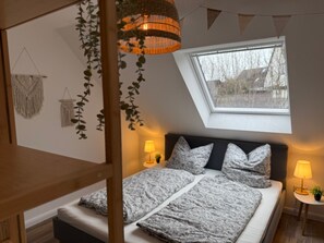 A bedroom with a bed, a skylight, a hanging light fixture, and wall decor. - Apartment 'Hygge' with Private Terrace, Private Garden and Wi-Fi (Hennstedt)