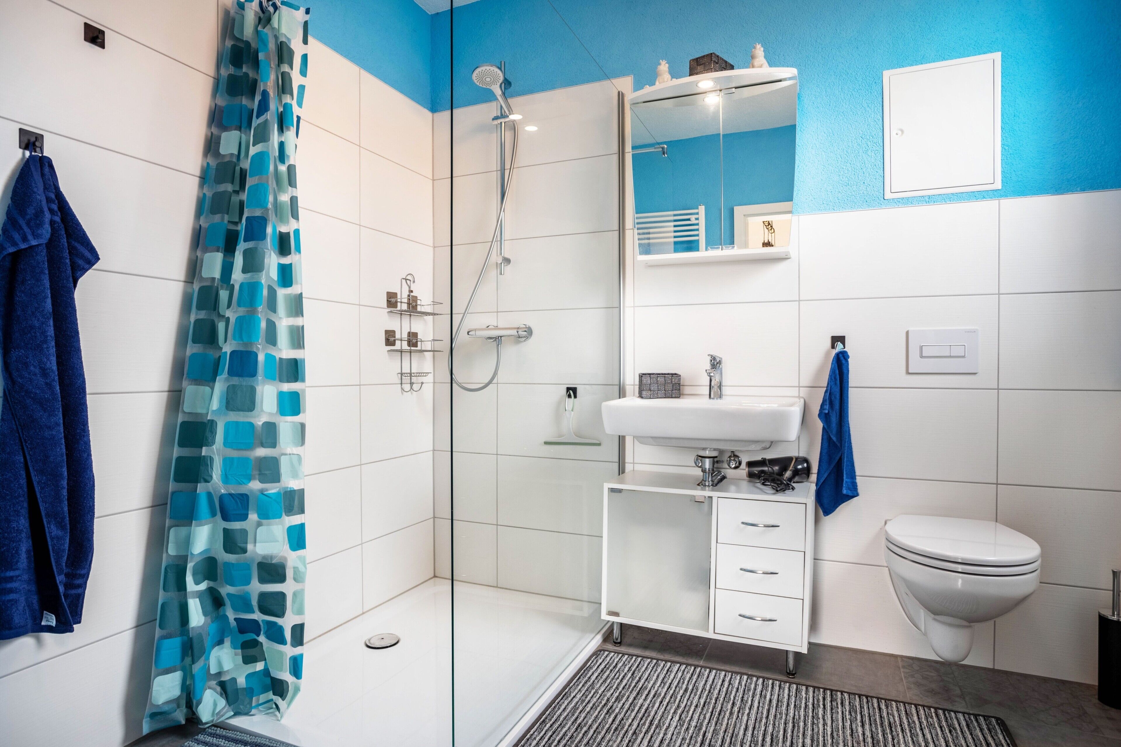 Ein Badezimmer mit Dusche, Toilette, Waschbecken und Spiegel.