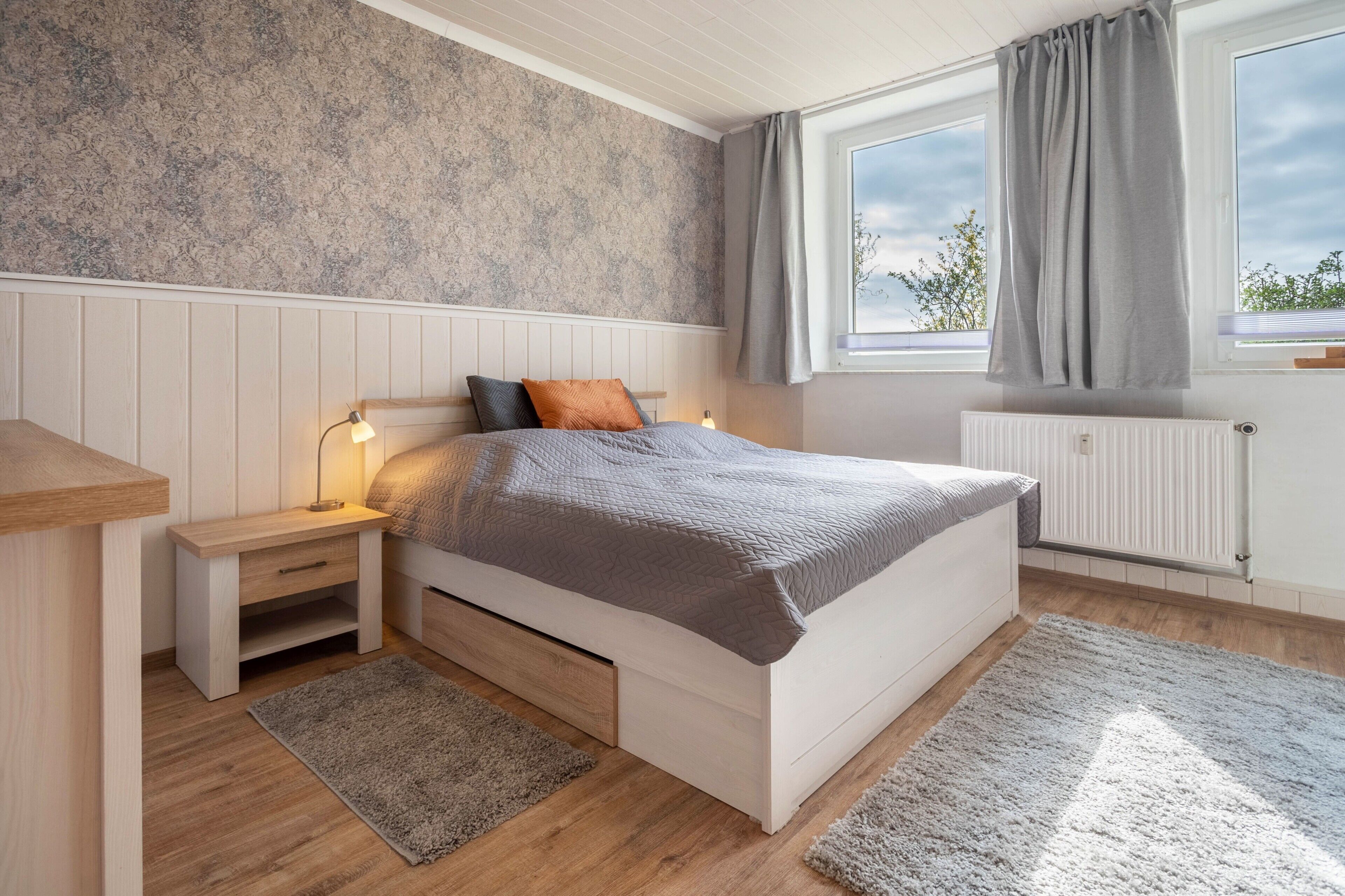 A bedroom with a bed, nightstand, and window.