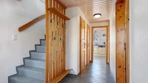 A staircase with wooden railings and a tiled floor leading to a kitchen area.