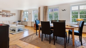A modern living room with a dining area, large windows, and a fireplace.