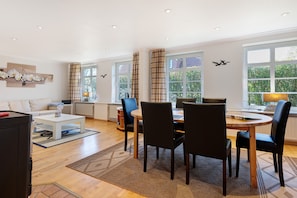 Een moderne woonkamer met een eethoek, grote ramen en een open haard.