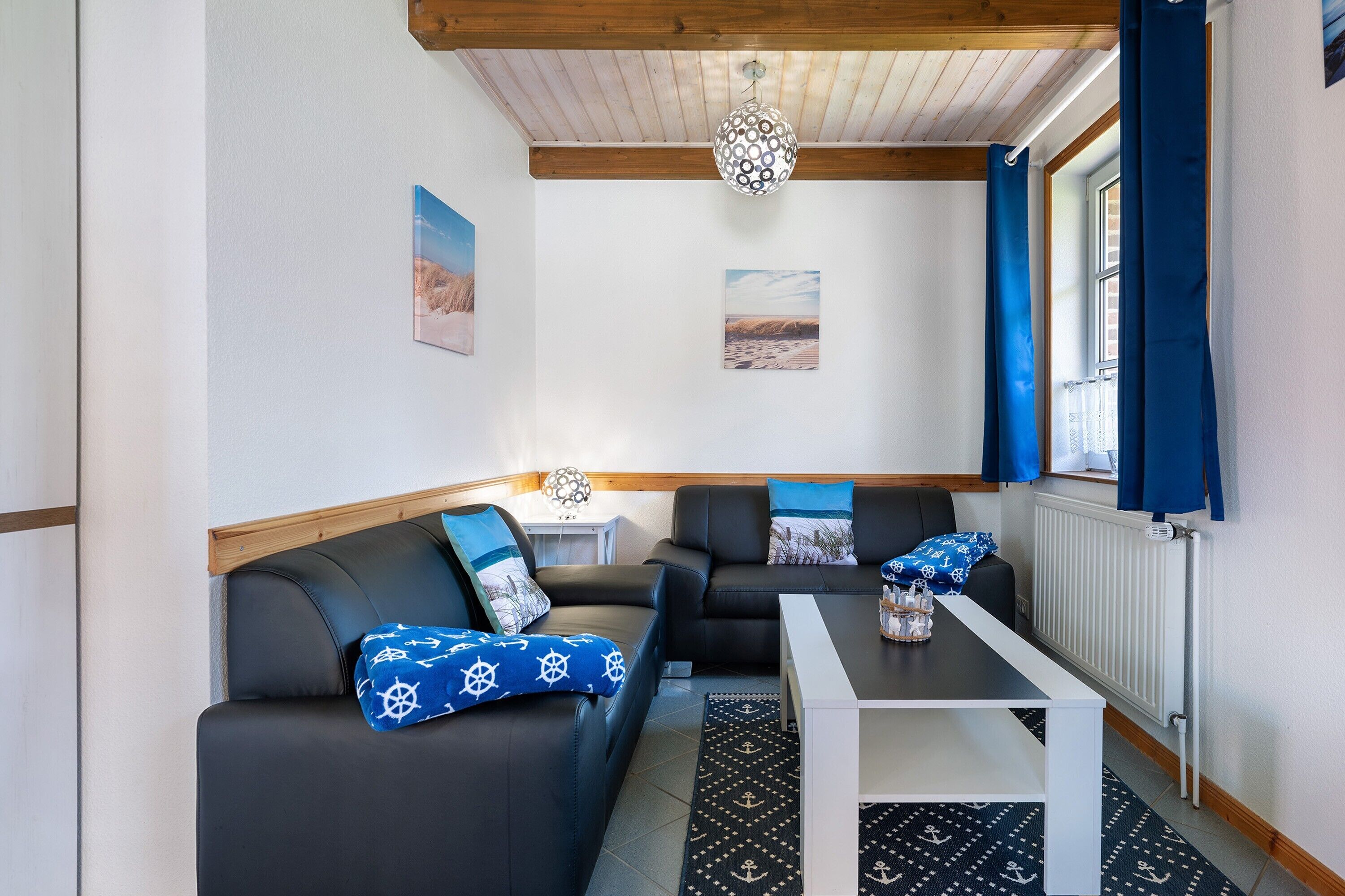 Quarto com sofá, mesa, luminária e janela com cortinas.
