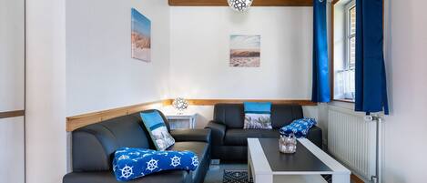 Quarto com sofá, mesa, luminária e janela com cortinas.