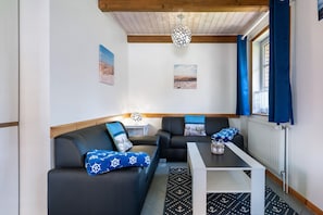 A room with a sofa, a table, a lamp, and a window with curtains. - Holiday Home 'Robbe' with Shared Terrace and Wi-Fi (Dagebüll)