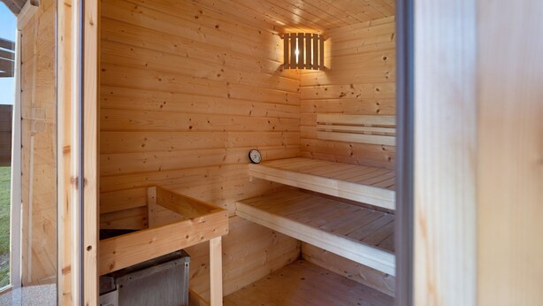 Un sauna en bois, doté de bancs et d’un panneau de commande visible.
