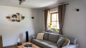 A modern living room with a sofa, a wooden coffee table, a lamp, and a wall art piece. - Apartment 'Bergliebe' with Mountain View, Balcony & WiFi (Weißbach an der Alpenstraße)