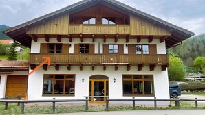 A two-story building with a balcony, a door, and windows. - Apartment 'Bergliebe' with Mountain View, Balcony & WiFi (Weißbach an der Alpenstraße)