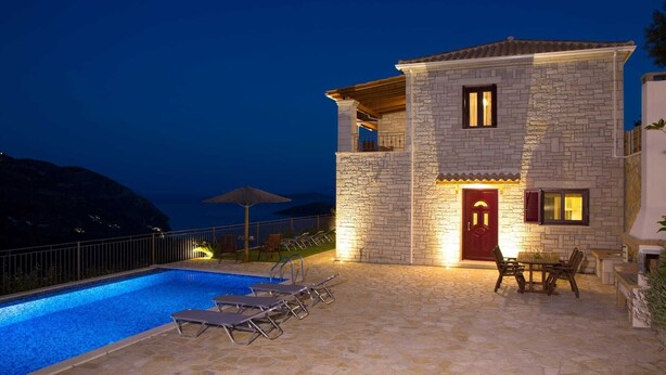 A stone villa with a swimming pool, outdoor seating, and a view of the sea at night. - Villa Magnolia Lefkada Greece (Lefkada)