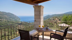 A balcony with a table and chairs, overlooking a coastal landscape with mountains and the sea. - Villa Magnolia Lefkada Greece (Lefkada)