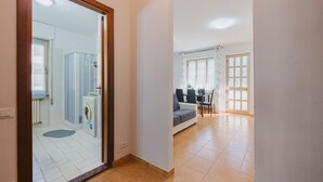 Amplia sala de estar con un sofá, una mesa de comedor y una cocina al fondo.
