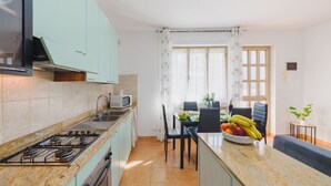 Una cocina funcional con estufa a gas, microondas y comedor con mesa y sillas.