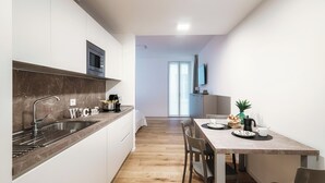 A modern kitchen with a built-in microwave, a sink, and a dining area with a table and chairs. - Suite JOIVY Porta Torre 76 (Como)