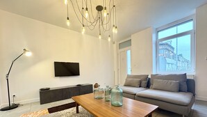 Un salon moderne avec une table basse en bois, un canapé gris et un téléviseur fixé au mur.