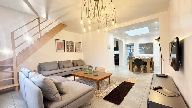 Un salon moderne avec un canapé, une table basse et un escalier.
