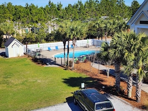 A residential area with a swimming pool, a small building, and a parked car.