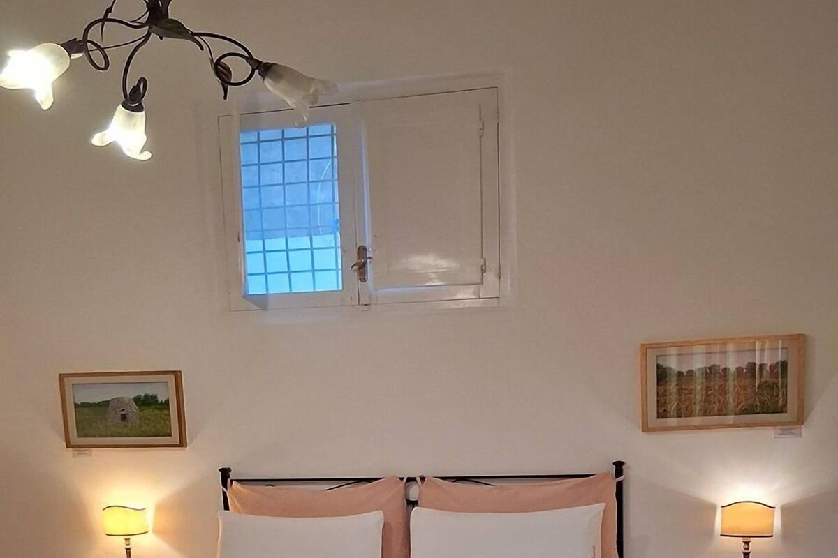 A bed with a metal frame, two bedside tables with lamps, a window with a grid pattern, and a patterned floor.