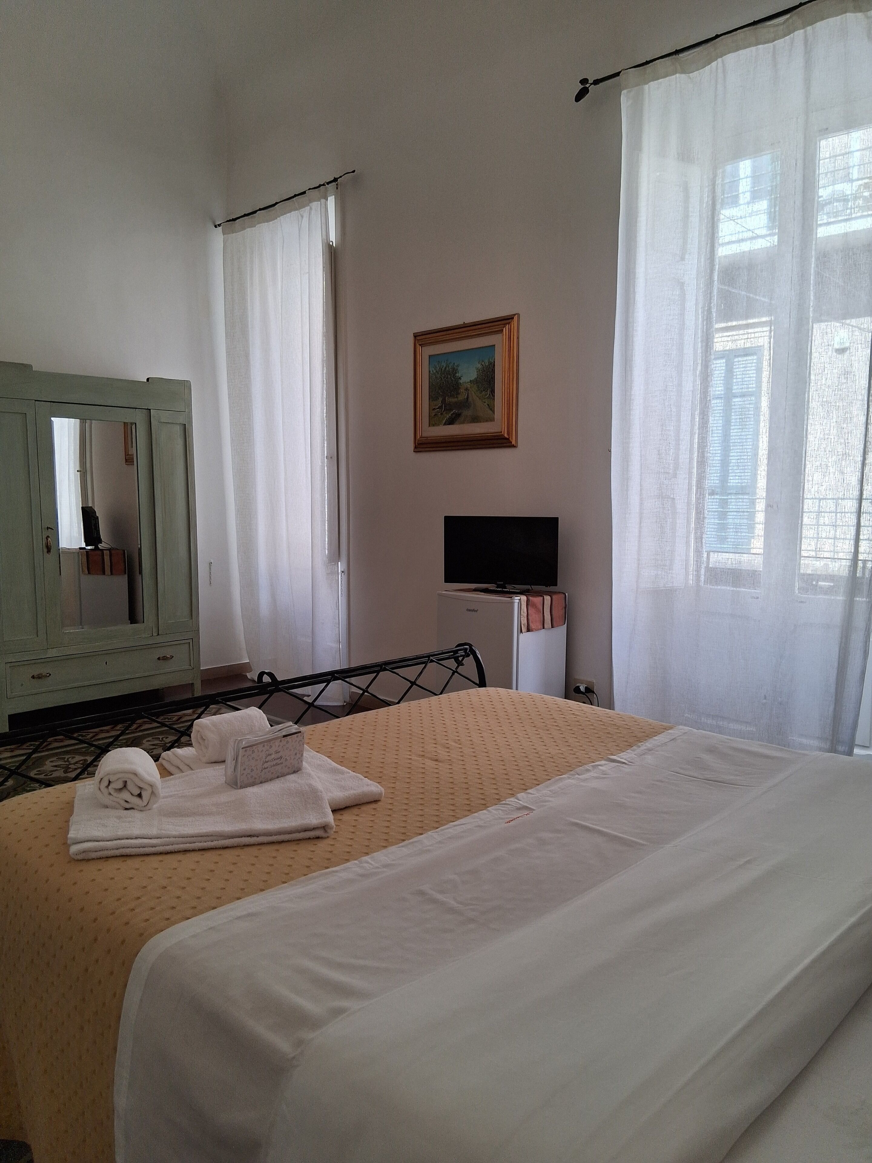 A hotel room with a bed, a television, a desk, and a mirror.