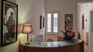 Un comptoir d’accueil agrémenté d’une lampe, d’œuvres d’art encadrées et d’un vase de fleurs.