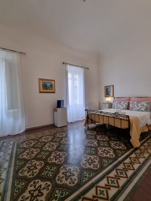 Cozy retreat with a large bed, bedside table, and radiator, set against a floral-patterned floor.