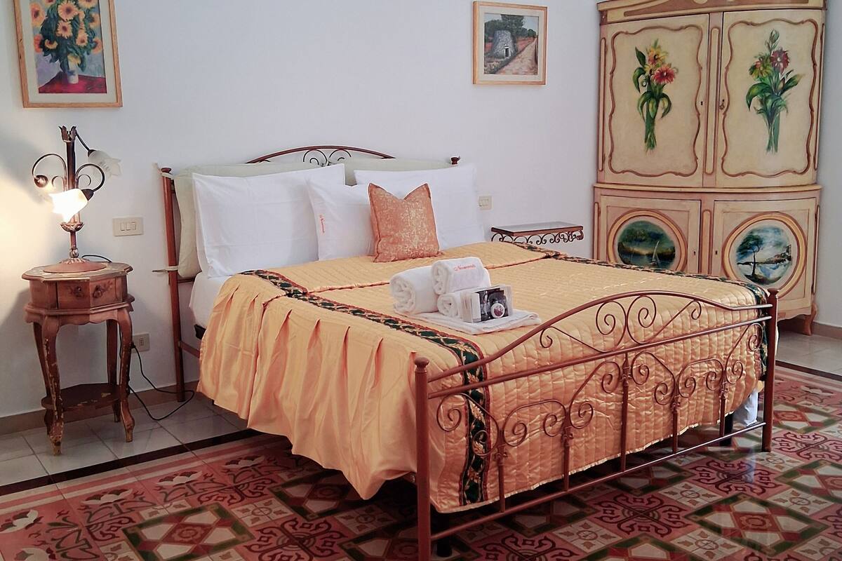 A bedroom with a bed, a nightstand, a dresser, and a chandelier.