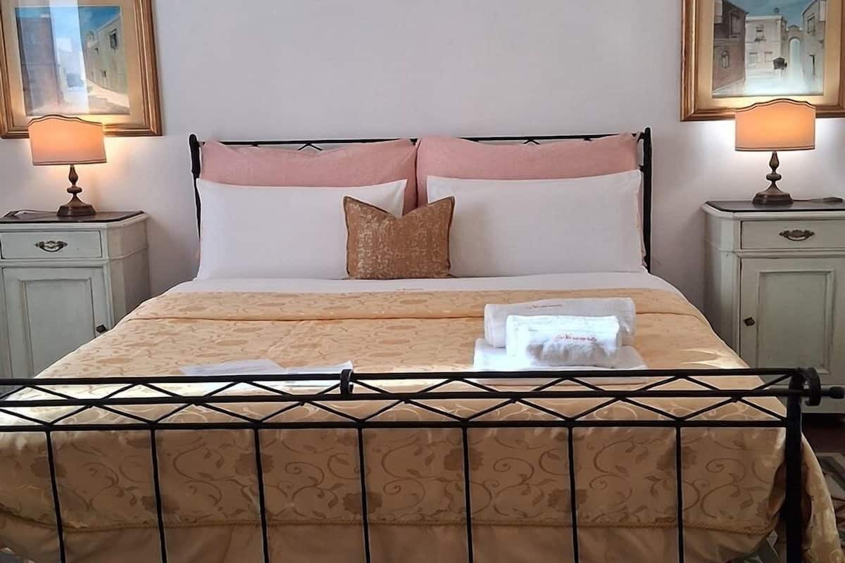A neatly made bed with a metal frame, two bedside tables with lamps, and a patterned floor.