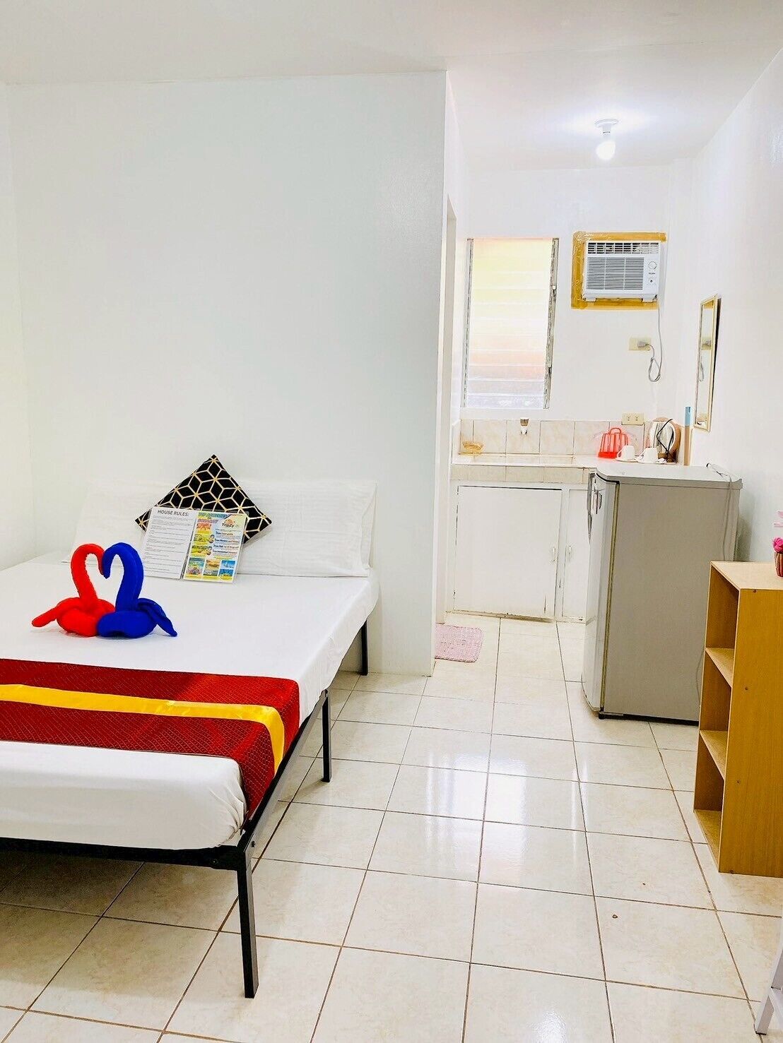 Una habitación pequeña y limpia con una cama, un escritorio y una kitchenette.