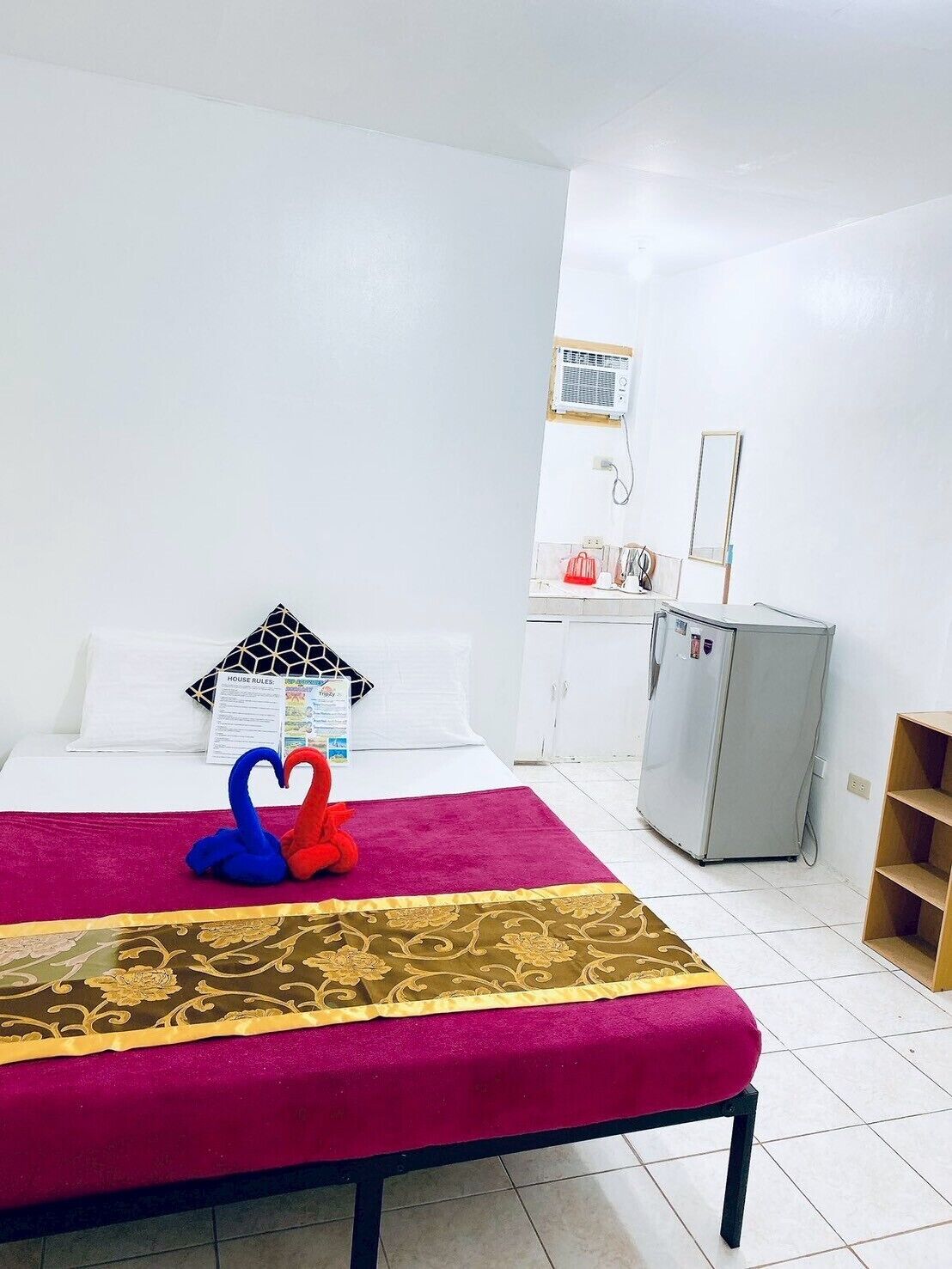 Une chambre d’hôtel équipée d’un lit, d’une petite kitchenette, d’un réfrigérateur et d’un miroir.