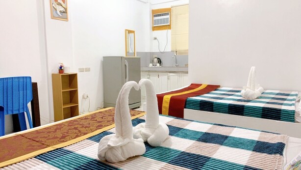 A hotel room with two beds, a small kitchenette, a mirror, and a window with blinds. - Glo's Space Boracay Dmall (Boracay Island)