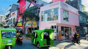 A street scene with a pink building featuring a large pink sphere on top, surrounded by various shops and vehicles. - Glo's Space Boracay Dmall (Boracay Island)