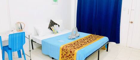 Una habitación con cama, escritorio, silla y ventana con cortinas azules.
