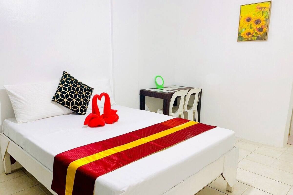 Ein Hotelzimmer mit Bett, Kissen, Nachttisch und Stuhl.