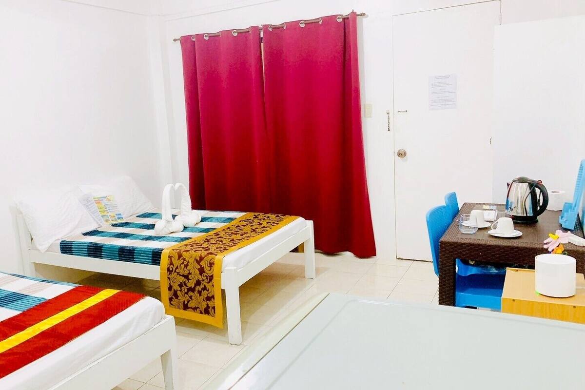 Ein Hotelzimmer mit zwei Betten, einem Esstisch und einem roten Vorhang.