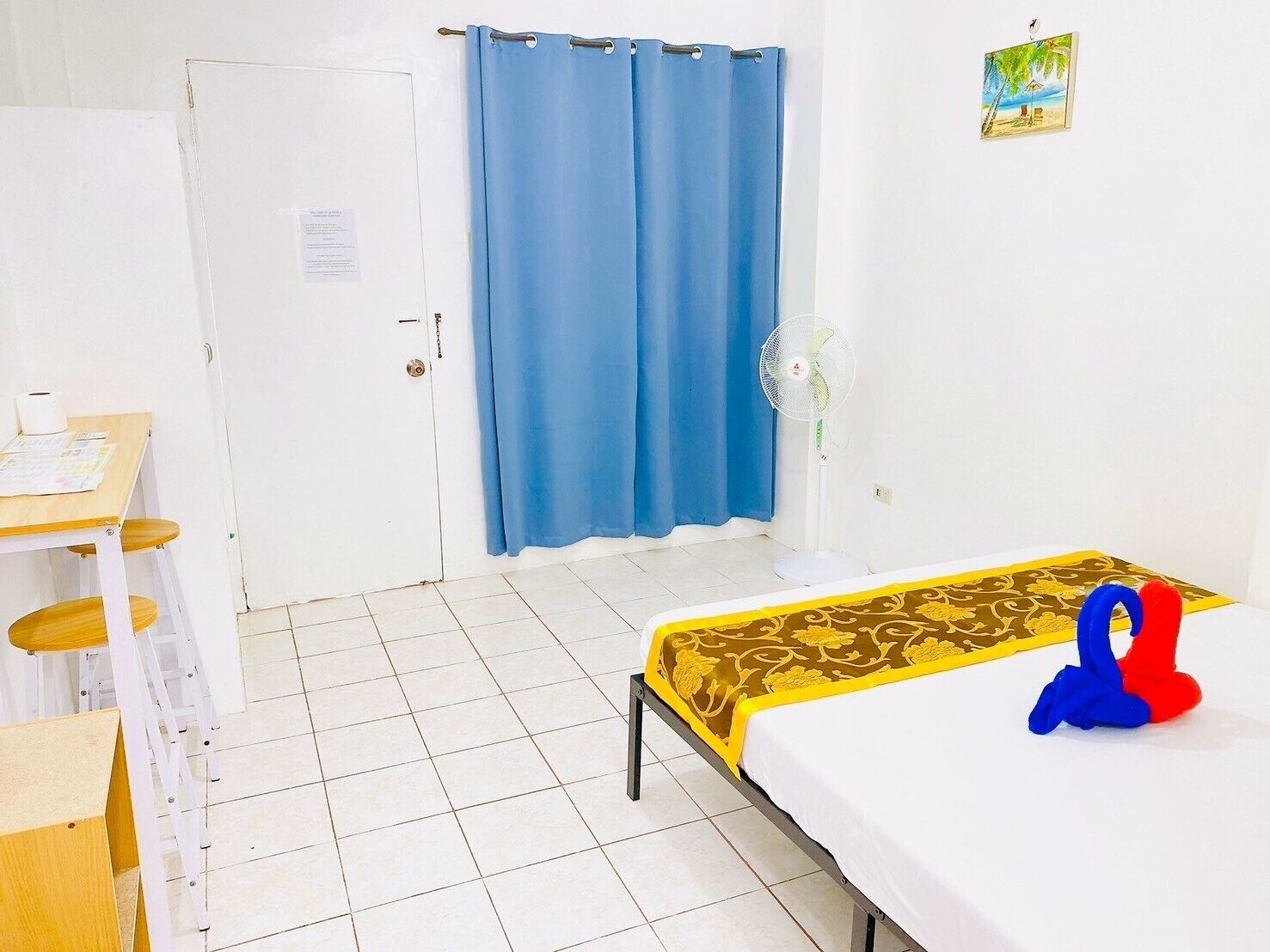 Una habitación pequeña y limpia con una cama, un escritorio y una cortina azul.