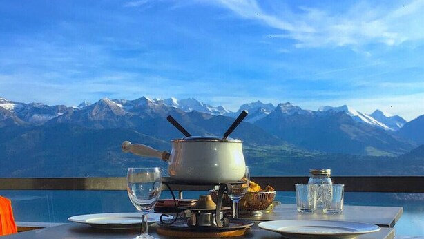 Une table dressée pour le dîner, avec vue sur des montagnes enneigées.