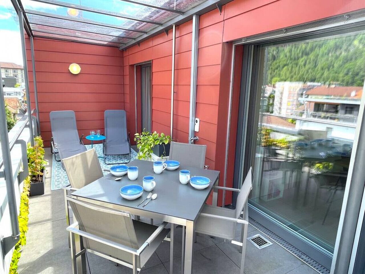 Ein Balkon mit Tisch für vier Personen, Stühlen und einem Blumentopf.