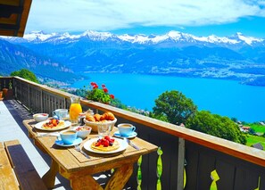 Ein Holztisch gedeckt mit Frühstücksleckereien und Blick auf eine malerische Berglandschaft.