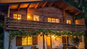 A log cabin with a balcony, outdoor seating, and a covered porch area.