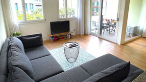 A modern living room with a grey sofa, a small coffee table, and a flat-screen TV.