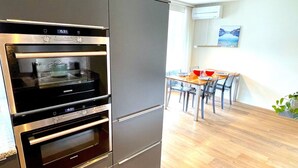 A modern kitchen with built-in ovens and a dining area with a table and chairs.