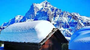 A snow-covered wooden cabin with a mountain backdrop. - Concierge, Lake Thun/Alps Scenic Views by SwissHut (Sigriswil)