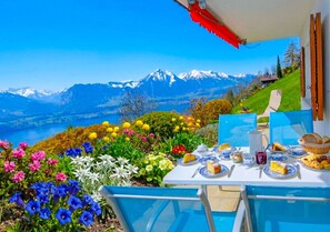 A table set outdoors with a mountain view, surrounded by colorful flowers. - Concierge, Lake Thun/Alps Scenic Views by SwissHut (Sigriswil)
