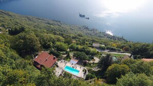 A residential area with a swimming pool, surrounded by lush greenery and a view of the sea.