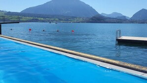Una piscina con agua azul cristalina, un muelle y montañas al fondo.