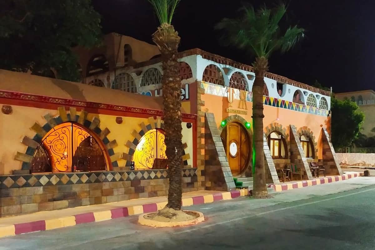 A building with arched windows and a decorative facade, featuring a palm tree in the foreground.