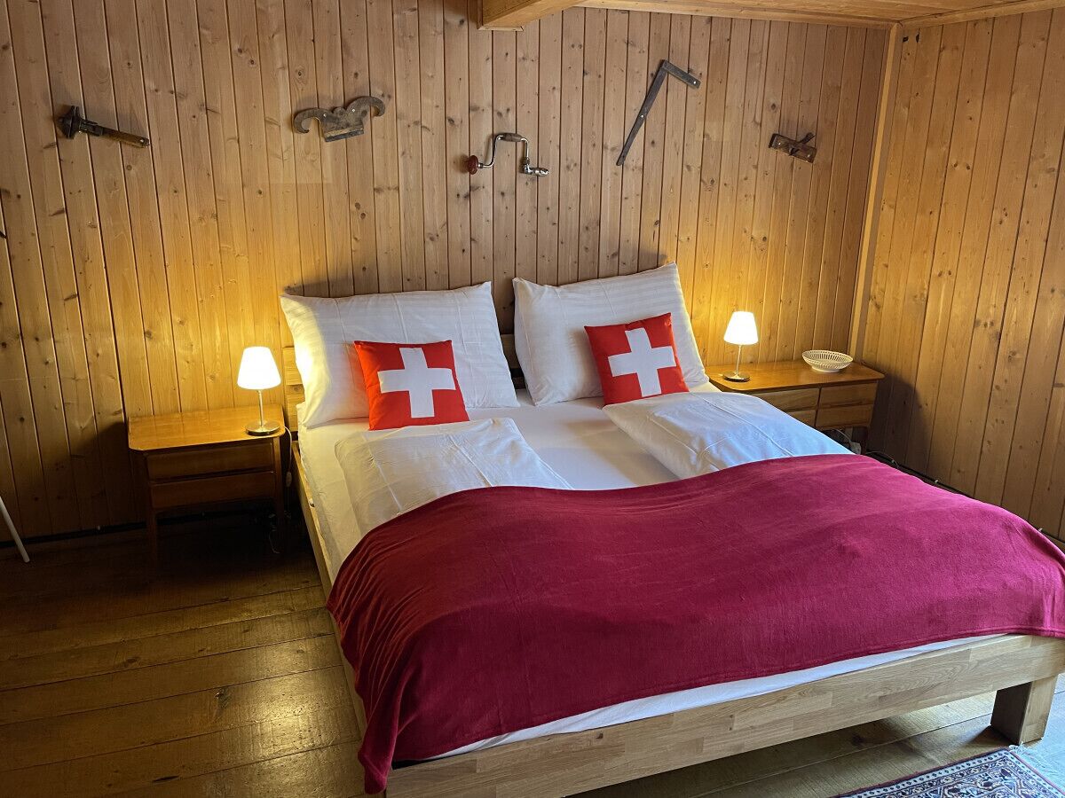 Ein Zimmer mit Holzwänden, einem Bett, zwei Nachttischen und einer roten Decke.