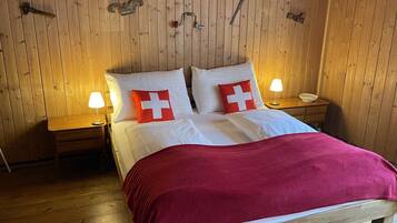 Ein Zimmer mit Holzwänden, einem Bett, zwei Nachttischen und einer roten Decke.